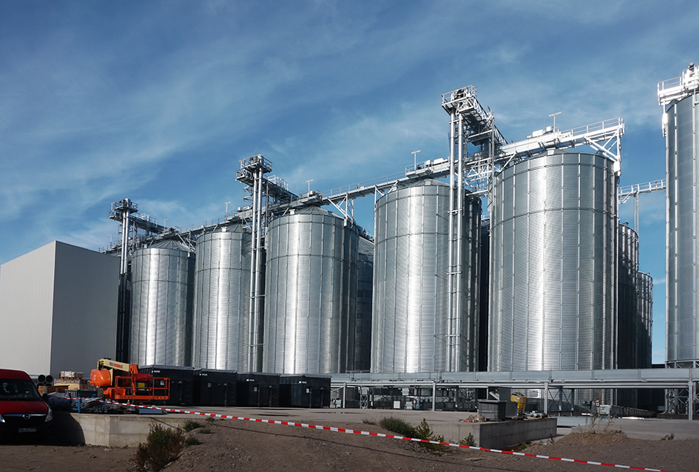 Verzinkte Silos und technische Anlagen des Rostocker Getreideterminals bei blauem Himmel