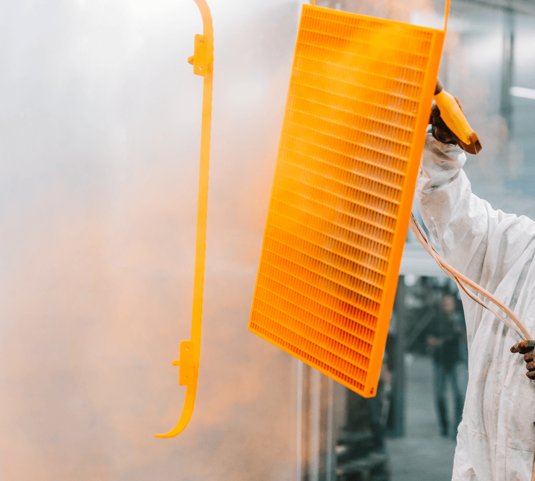 Detailaufnahme eines orangefarbenen Gitterelements während der farbigen Pulverbeschichtung