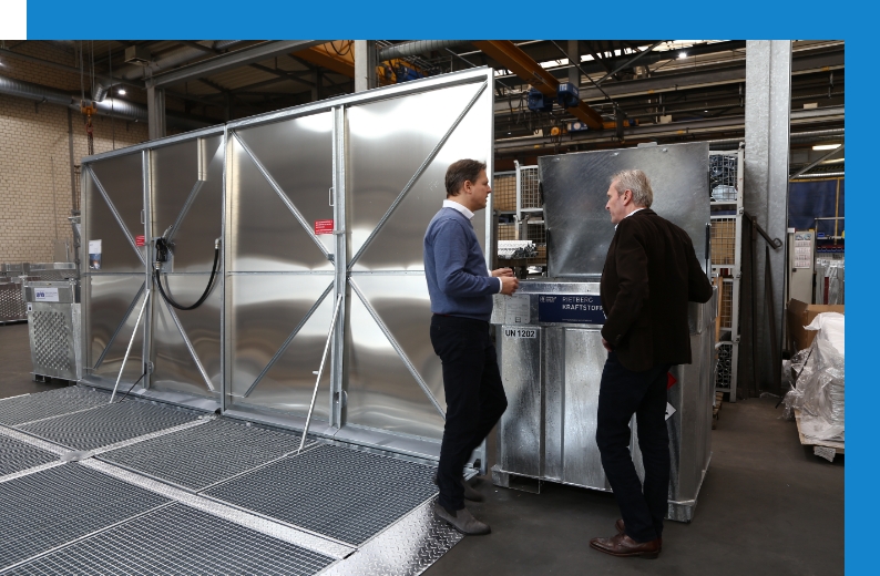 Guido Röttgers und Jens Sprick im Gespräch vor einem Intermediate Bulk Container (IBC) in der Produktion
